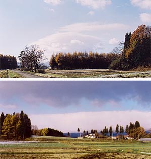 （写真2）上空で西風が吹いているとき、奥羽山脈の風下にできたレンズ雲と山脈にかかる風枕（フェーン壁）。2005年11月19日12時30分 雫石にて吉野撮影 © （上）風下波動によるレンズ雲。上空の西風は画面右から左へ吹いている。 （下）遠景の白いのが風枕。西風は画面奥から手前に吹く。画面上部の黒い雲はハイドローリックジャンプによる低い雲。
